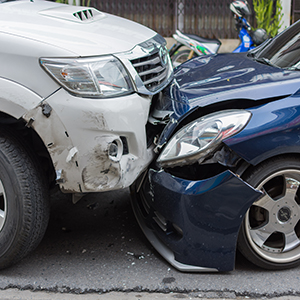 A white SUV and a blue sedan have collided head-on, with significant damage to both vehicles.