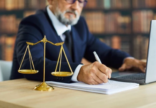 Criminal defense attorney reviewing legal documents beside scales of justice