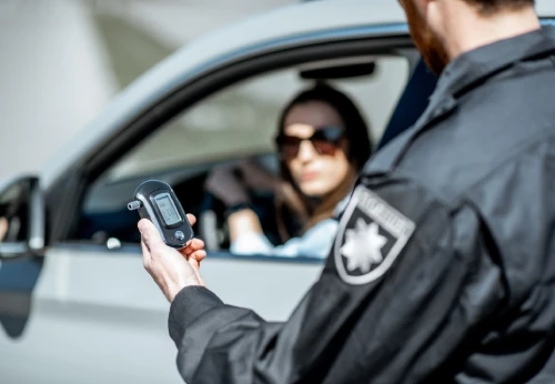 Police officer conducting a breathalyzer test during a DUI traffic stop