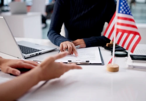 Immigration attorney reviewing documents with a client beside an American flag